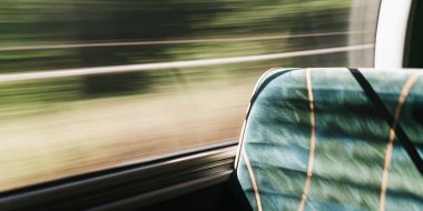Bulanık yeşillik ve yüksek hız hareketini gösteren bir yolcu treni penceresi. Manzaralı bir yolculukta hareket hissi camın içinden geçer..