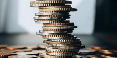 Servet ve finansal riskin kırılganlığını sembolize eden eğik bir madeni para yığınının yakın plan görüntüsü. Bu resim, istikrarsız yatırımlar ve iş dünyasındaki ekonomik belirsizlik kavramlarını gösteriyor.