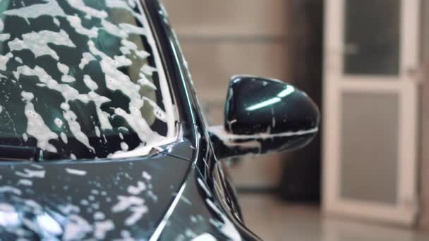 Czarny samochód sedan po umyciu w pianie z boku i pod kątem przednim — Wideo stockowe