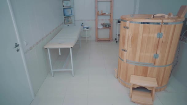 Spa room with cedar phytobarrel a stool is placed next to it, couch and a shelf — Stock Video