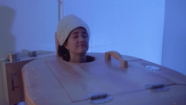 La cabeza de la niña de cerca se asoma desde el barril de cedro caliente phyto en la sala de spa — Vídeos de Stock