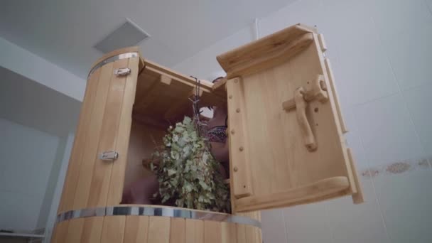 Loseup of open hot cedar phytobarrel. Dentro se sienta chica y cuelga escoba para baño — Vídeo de stock