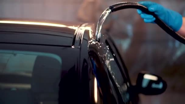 Meester wast van deur, raam van zwarte sedan met slang met water closeup zeldzaam uitzicht — Stockvideo