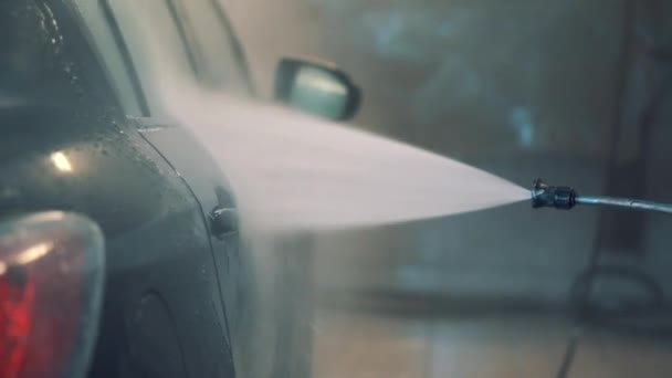 Man washes window, door,mirror,roof of sedan with water hose in service closeup — 비디오