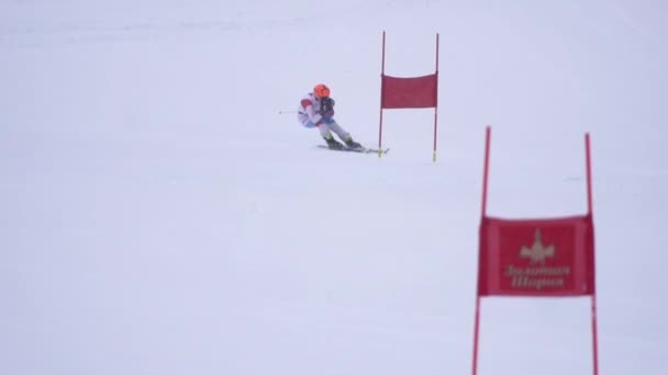 Спортсмен катится со скоростью на лыжах в обход флагов, застрявших в замедленном движении снега — стоковое видео