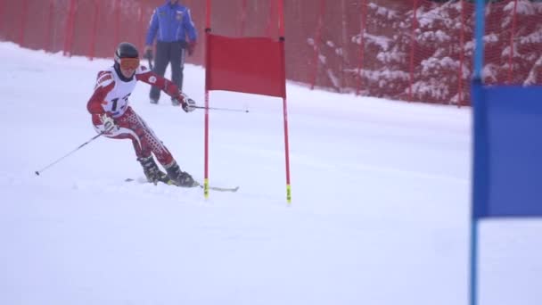 Спортсмен катится со скоростью на лыжах в обход флагов, застрявших в замедленном движении снега — стоковое видео