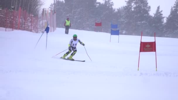 Idrottsman rullar spår i hastighet på skida förbi flaggor fastnat i snö slowmotion — Stockvideo