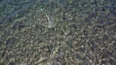 Yumuşak dalgalar, sığ ve şeffaf bir denizin üzerinde yavaşça hareket eder. Temiz su, tipik Akdeniz Yunanistan 'da olduğu gibi denizin dibindeki çakıl taşını ortaya çıkardı.