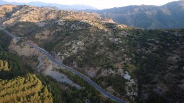 Yunanistan 'ın dağlık kesimindeki kanyon vadisinin yanındaki ulusal otoyol gün batımında sık köknar ormanı ve dik kayalık dağı geçiyor. Trafik yok, sadece bir kamyon geçiyor. Direkt gidiş yolu. Ufukta tepe var. Avrupa. Yunanistan.