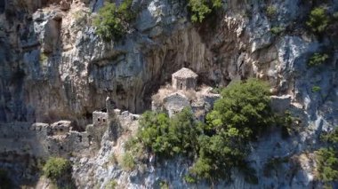 Taş duvarlar ve yıkılmış bir kilise dağın tepesindeki bir mağaradan ortaya çıkıyor. Terk edilmiş Bizans manastırı Lousios vadisi, Yunanistan ve Avrupa 'daki sarp kayalıklara bakıyor.