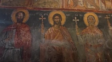 DIMITSANA, GREECE - 08-18-2025: Haçı tutan Aziz Artemius ve Aziz Minas freskleriyle birlikte antik Bizans Ortodoks kilisesi. Düşük ışık, Yunanistan ve Avrupa 'da kutsal sanat eserlerini koruyor.
