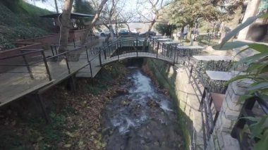 Yunanistan 'da bir dağ köyü meydanı kışın kıyıları boyunca dökülen yapraklarla akan hızlı bir nehirle kesişiyor.