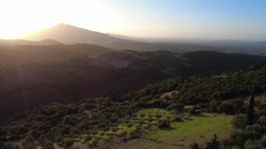 Dağların arkasındaki batan güneş, Yunanistan ve Avrupa 'daki zeytin ağaçları, tarlalar ve geniş vadi manzaralarına sıcak bir ışık tutuyor..