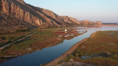 Uzak bir dini yapı yansıtıcı su ve doğal çöl arazisi yakınlarında toprak bir yol boyunca görünür. Yunanistan ve Avrupa 'da huzur dolu ruhsal manzara.