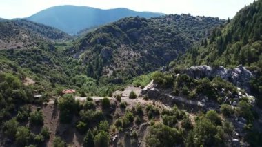 Yunanistan ve Avrupa 'daki yumuşak gün ışığı altında, derin vadilerin üzerindeki çalılar ve çam ağaçları ve ormanlık tepelerin arasında küçük bir çinko çadırı yer alıyor..