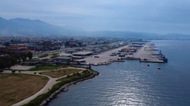 Şehir kıyısı yeşil park alanlarını yoğun liman tesisleri kargo birimleri ve savaş gemisiyle Yunanistan ve Avrupa 'da açık mavi ufuk çizgisini birleştiriyor.