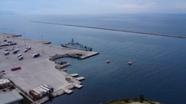 Yunanistan ve Avrupa 'daki sakin mavi sular boyunca büyük beton iskeleli vinç konteynırları ve kenetlenmiş deniz gemisiyle ticari liman.