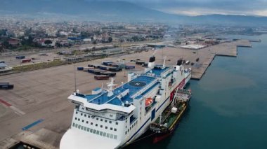İskeleye demirlemiş beyaz ve mavi feribot motorları çalışıyor ve sanayi kıyı şehrinin üzerinde yoğun duman yükseliyor. Yunanistan ve Avrupa 'daki kahverengi kirlenmiş sular limanı çevreledi.
