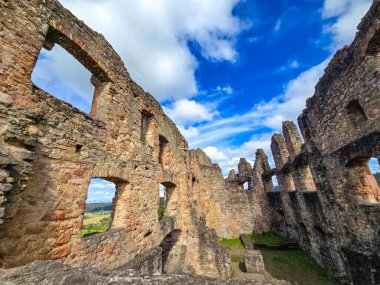 Hochburg Kalesi 'nin (Emmendingen, Almanya) korunmuş Gotik pencere açıklarından geçen Kara Orman manzarasının pitoresk bir görüntüsü. Güneş ışığı, yemyeşil bir vadinin arka planına karşı kırmızı kumtaşı dokusunu vurgular.