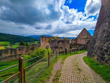 Düşük savunma duvarlarının ve Hochburg 'un temellerinin güneşli panoramik görüntüsü. Merdivenlerden bakınca, Baden 'deki en büyük kale kalıntılarından birinin geniş ölçekli olduğunu görüyoruz. Ren Vadisi ve Vosges Dağları' na bakıyor..