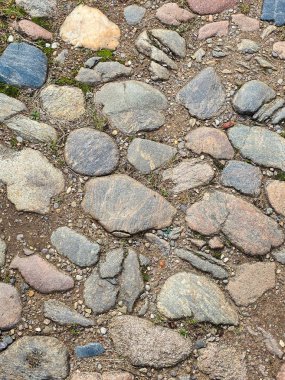 Pürüzsüz nehir çakıl taşları ve kaldırım taşlarından yapılmış, boşluklarda canlı yeşil yosun ve çimen yetişen kırsal taştan geçitin yüksek açılı görüntüsü. Organik arka plan ya da mimari kavramlar için mükemmel..