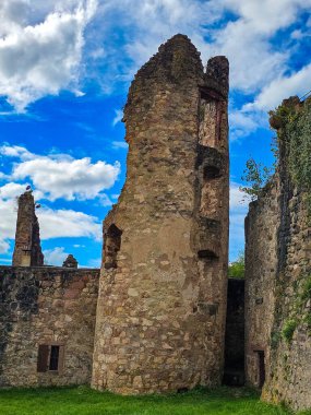 Hochburg Kalesi 'nin yüksek ortaçağ duvarlarının geniş açılı görüntüsü. Geleneksel bir kaldırım taşı yolu, Kara Orman bölgesinde dramatik bir gökyüzüne karşı inşa edilen muazzam tahkimatların yanında yer alıyor..