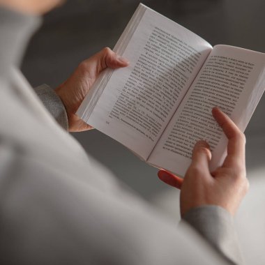 Adam elinde açık bir kitap tutuyor ve başyazı okuyor.