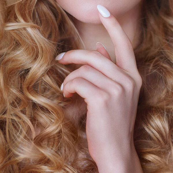 Woman's hand with white manicure touches the chin emotion of thinking close-up