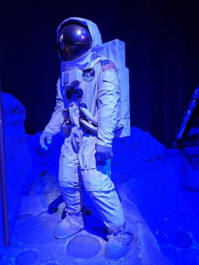 Mavi ışıklandırılmış ay ortamında etkileyici bir astronot kıyafeti. Detaylı giysi uzay görevleri sırasında astronotların kullandığı ekipmanı temsil ediyor. Uzay keşiflerindeki önemini vurguluyor..