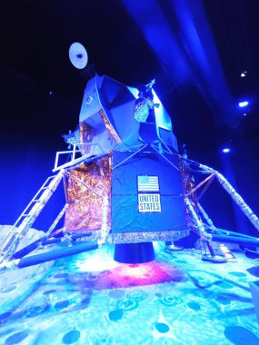 Ay modülünün etkileyici bir kopyası, mavi ışıklarla aydınlatılmış ve ABD amblemi vurgulanmış. Ayar, uzay görevleri ve ay keşifleri çağını anımsatan bir atmosfer yaratıyor..