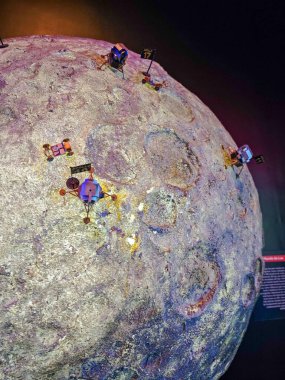 Ay yüzeyinin detaylı bir tasviri, üzerinde çeşitli uzay araçları bulunan üç boyutlu bir Ay modelidir. Konferansta kraterler ve yüzey dokuları, keşif ve bilimsel merakı çağrıştırıyor. Yumuşak ışıklandırma büyütür