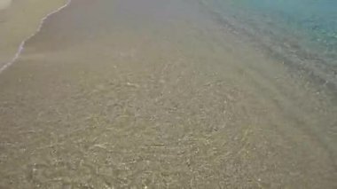 Tropiklerde deniz kıyısında. Sarı kumun üzerinde bir ışık dalgası yuvarlanıyor. Tatilde sakin ve sessiz.