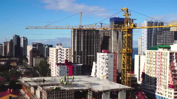ビジネスの構築 海岸沿いの都市に高層ビルを建設する建築家のチームワーク 高層ビルや青空を背景にしたタワークレーン — ストック動画