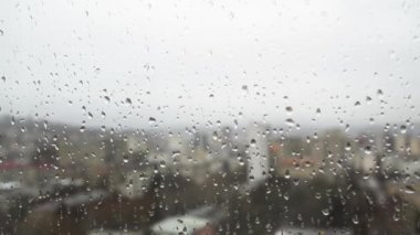 Pencerenin dışındaki bardaktan yağmur damlaları akıyor. Bulutlu havada kasvetli gökyüzü. Hüzünlü ruh hali.