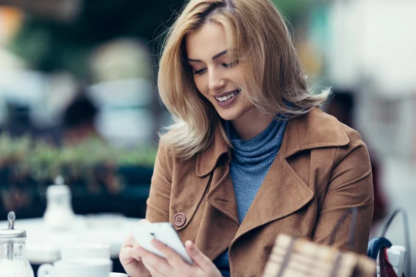 Усміхнена жінка дивиться на мобільний телефон — стокове фото
