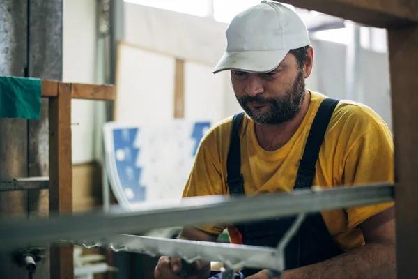 Bärtiger Arbeiter mit Mütze am Arbeitsplatz — Stockfoto