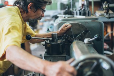 Metal işleme makine üzerinde çalışan ciddi adam