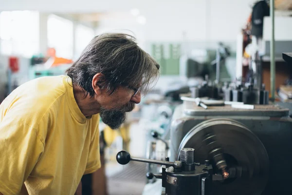 Metal işleme makine üzerinde çalışan ciddi adam