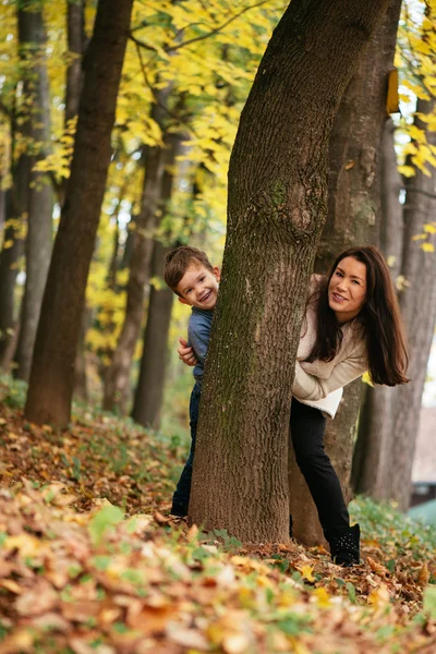 Mother and son hiding behind tree — Stock Photo, Image