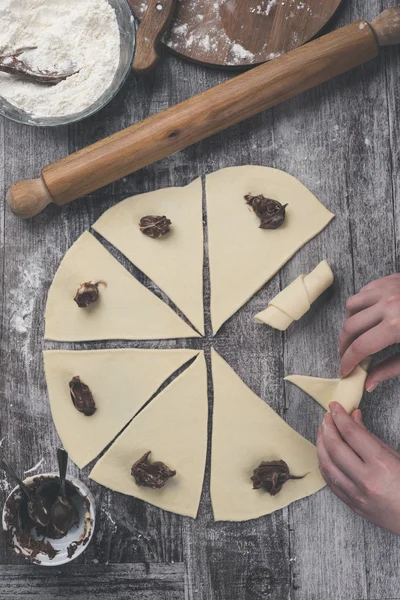 Manos haciendo rollos con crema de turrón — Foto de Stock