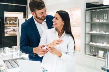 Modern kuyumcuda alışveriş yapan güzel bir çift. Pahalı bir yüzük ve bilezik takmış bir kadının elini yakın plan çek..