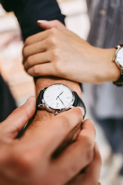 Beautiful couple enjoying in shopping at modern jewelry store. Close up shot of human hand holding expensive watch.