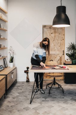 Stüdyosunda ya da atölyesinde çalışan kağıt tasarımcısı ve sanatçı. Virüs salgınına karşı koruyucu yüz maskesi takıyor..