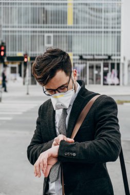 Şehir caddesinde koruyucu maskesiyle yürüyen bir iş adamı. Virüs salgını kavramı.