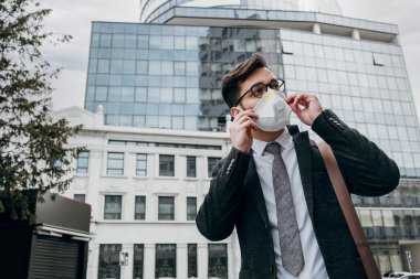 Şehir caddesinde telefon kullanan koruyucu maskeli bir iş adamı. Virüs salgını veya salgın hastalık konsepti.
