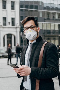 Şehir caddesinde telefon kullanan koruyucu maskeli bir iş adamı. Virüs salgını veya salgın hastalık konsepti.