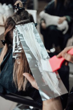 Kuaför kadın saçı boyuyor, müşterisine folyoyla saç renkleri yapıyor..