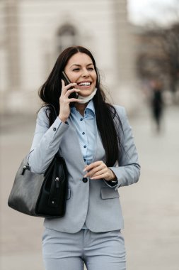 Zarif bir kadın boş bir caddede yürüyor ve kendini tehlikeli grip ya da virüsten korumak için koruyucu maske takıyor. Gülümsüyor ve iyimser. Corona virüsü veya Covid-19 Olumlu kalmaya devam et.