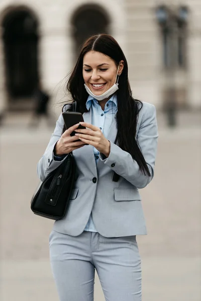 Elegant woman walking on empty city street and wearing protective mask to protect herself from dangerous flu or virus. She is smiled and optimistic. Corona virus or Covid-19 stay positive concept.