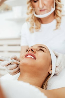 Güzel ve çekici yetişkin kadın serumla profesyonel cilt bakımı görüyor..